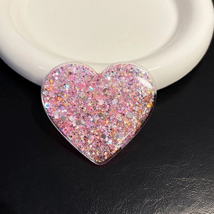 Macro view of heart-shaped phone grip featuring pink glitter and sequins in resin