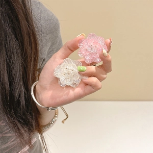 Vue détaillée de supports de téléphone en forme de fleurs en résine rose et blanche en main