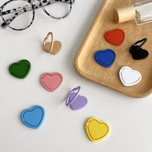 Colorful heart-shaped adhesive phone ring stand holders displayed on a clean white surface.