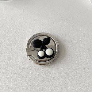Detailed close-up of a silver phone ring holder with a minimalist black and white cherry motif