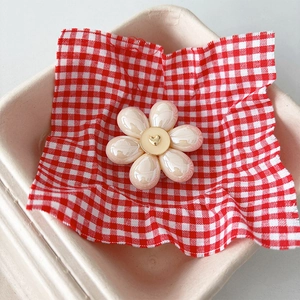Détail d'un support de téléphone fleur blanc perle avec cœur doré sur un tissu à carreaux
