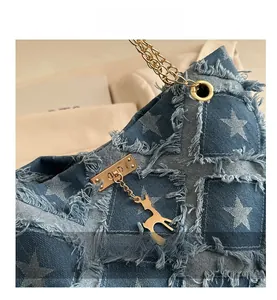 Detail of denim tote bag featuring white stars, frayed edges, and golden deer pendant