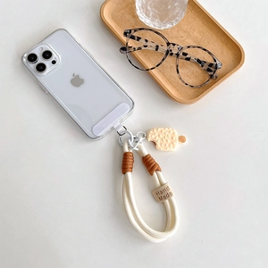 Macro shot of cream braided phone strap with 'Hand Made' label and waffle charm detail