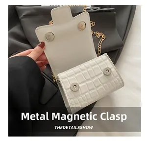 Close-up of metal magnetic buckle closure on stone pattern mini bag