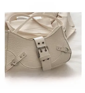 Detail view of cream crocodile texture leather with silver metal rivets and buckle