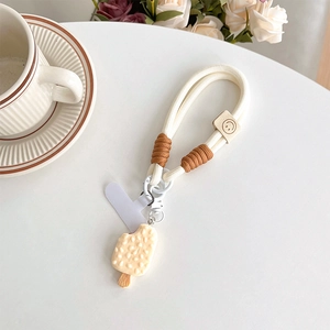 Close-up of woven cream phone lanyard with ice cream charm and smiley face leather tag