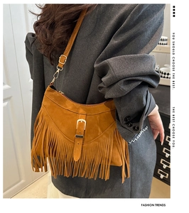 Detail of a brown suede crossbody bag with long tassels and golden metal buckle closure