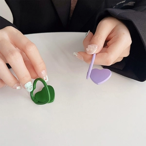 Detailed macro shot of solid color heart-shaped phone ring holders in green and purple