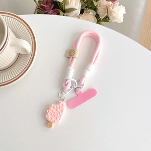Detail of pink woven phone lanyard with cute ice cream pendant and leather smile charm