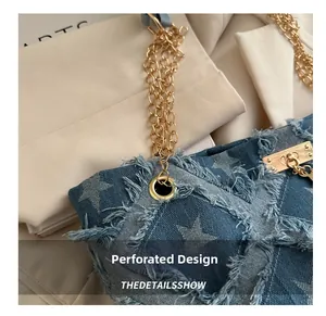 Detail of denim tote bag with star patterns, frayed edges, and golden metal chains