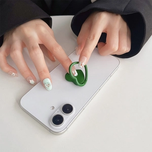 Detailed close-up of a green heart-shaped phone ring stand attached to a white smartphone