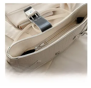 Detail of smooth silver zipper and crocodile embossed texture on cream baguette bag
