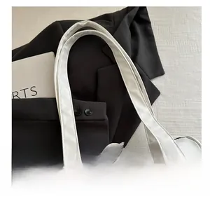 Close-up of white leather barrel bag handle with silver metal buckle and soft texture