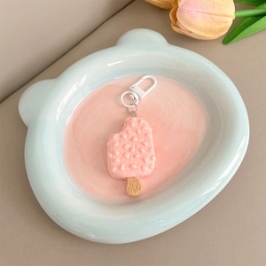 Detail of pink ice cream charm strap with textured surface on a bear ceramic tray