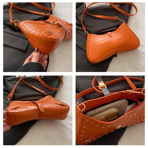 Detail view of orange crocodile-embossed underarm bag with gold studs and heart-shaped base