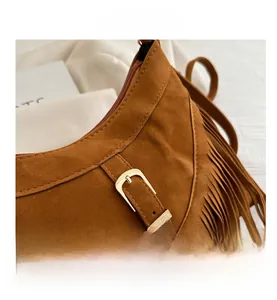 Close-up of brown suede hobo bag featuring bohemian fringe and decorative belt detail