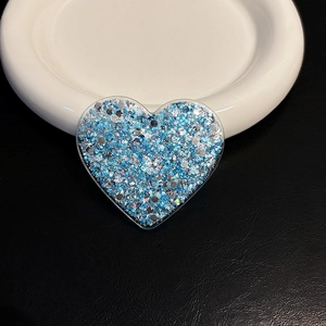 Macro detail of heart-shaped phone grip with sparkling blue and silver glitter flakes