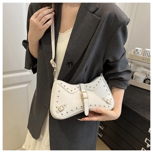 White croc-embossed crescent shoulder bag with gold studs and hardware on model
