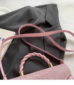 Détail d'un sac à main rose à paillettes avec poignées tressées et bandoulière réglable