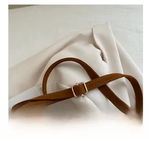 Detail of adjustable dark brown suede shoulder strap with golden square metal buckle