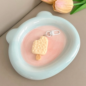 Close-up of ice cream charm phone lanyard with white metal hook on ceramic tray
