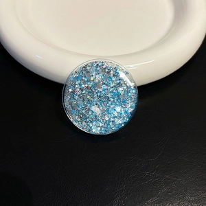 Detailed view of round phone grip with blue and silver glitter sequins on ceramic plate