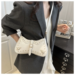 Detail of white crocodile texture crescent bag with gold studs and biker style buckles