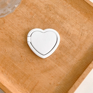 Detailed view of a minimalist white heart-shaped stick-on phone ring holder stand.