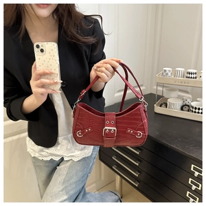 Close-up of red crocodile pattern shoulder bag with silver buckles and punk rivets