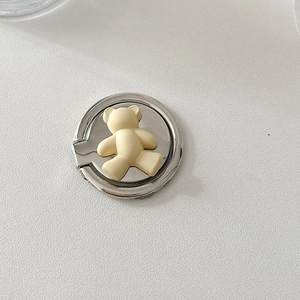 Close-up of a silver metal phone ring holder featuring a cute cream 3D teddy bear design