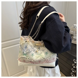Detail of star patchwork tote bag with frayed edges and golden deer pendant accessory