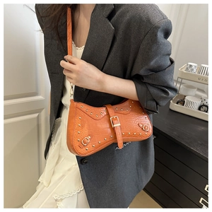 Detail of orange crocodile pattern crossbody bag with gold stud rivets and punk metal hardware