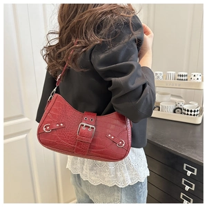 Detail of burgundy crocodile pattern underarm bag with silver buckle worn with blazer