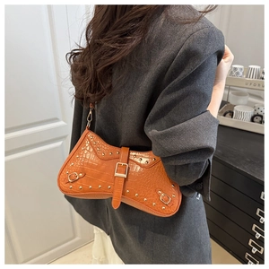Detail of orange faux leather shoulder bag with crocodile texture and gold hardware studs
