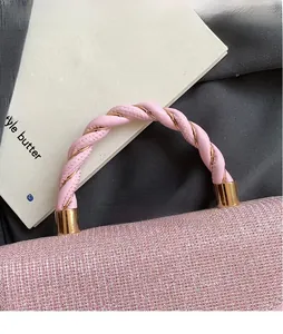 Gros plan d'un sac à main rose pailleté avec poignée en métal tissé style luxe