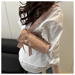 Close-up of pink cylinder shoulder bag featuring a decorative leather bow and metal ring