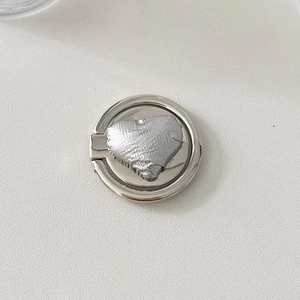 Detailed view of silver heart-shaped metal phone ring holder with unique foil-like texture