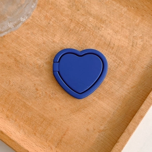 Close-up of a royal blue heart-shaped phone ring stand holder on a natural wooden tray