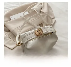 Detail showing the white embossed leather texture and vintage gold buckle on the handbag