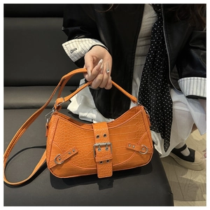 Close-up of orange crocodile pattern crossbody bag with silver buckles and rivets