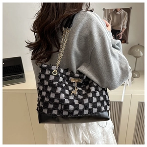 Detail of checkered tote bag featuring frayed edges, chain strap and deer charm