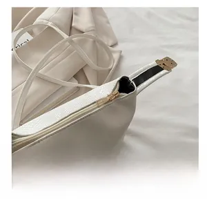 Detail showing the smooth gold metal zipper on white snakeskin patterned crossbody bag