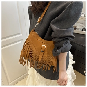 Brown suede crossbody bag featuring long fringe detail and metal buckle strap design