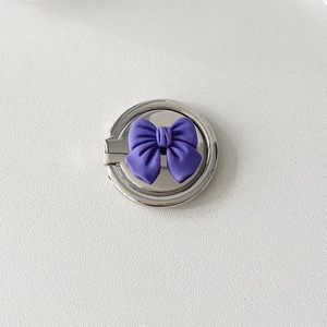 Detailed macro view of silver metal phone ring holder with a purple 3D bow design