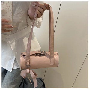 Dettaglio della borsa a cilindro rosa con fibbia in metallo e ciondolo a fiocco decorativo
