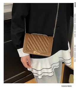 Detail of brown velvet crossbody bag featuring diagonal stitching and golden metal lock