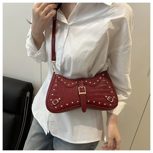 Detail of burgundy crocodile-embossed leather handbag with rivets and silver studs