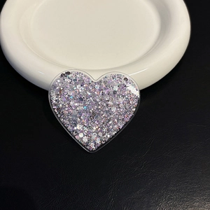 Detail showing a heart-shaped glitter phone socket with sparkling sequins on leather