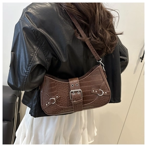 Detail of a brown crocodile pattern shoulder bag with a silver square buckle on a model