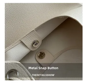 Gros plan du fermoir magnétique et de la texture cuir grainé du sac à bandoulière